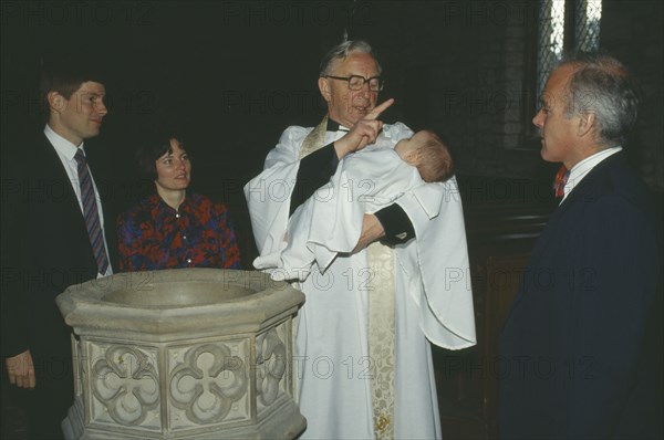 ENGLAND, Yorkshire, Religion, Church of England baptism.  Priest makes sign of the cross on the babys forehead with holy water from font.