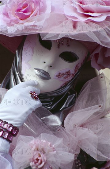 ITALY, Veneto, Venice, Venice Carnevale. Close up portrait of a female figure dressed in a white and pink floral costume and mask