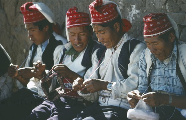 PERU, Puno, Lake Titicaca, Taquile Island.  Line of men knitting.