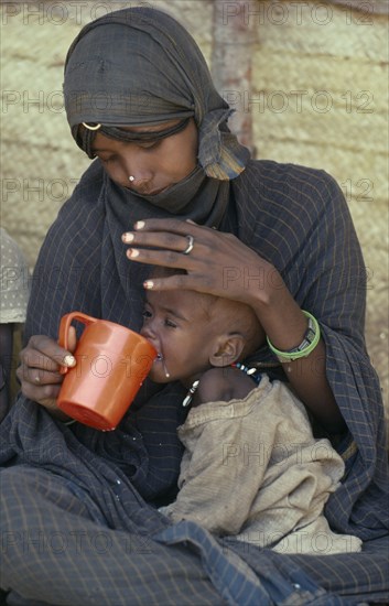 SUDAN, General, Mother feeding child at Sinkat feeding centre for malnourished children run by the Red Cross and Red Crescent.