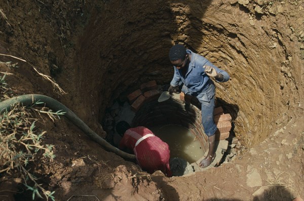 UGANDA, Aid, Trainee woman brick layer lining newly dug well near Jinja for project funded by Comic Relief.