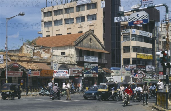 INDIA, Karnataka, Bangalore, Street scene.  Traffic at traffic lights with old and modern architecture and advertising hoardings.