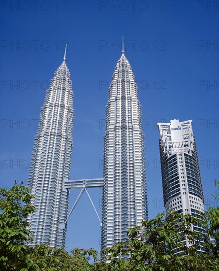 MALAYSIA, Kuala Lumpur, Petronas Twin Towers. Angled view looking up at the multi storey buildings housing corporate headquarters and nearby Maxis building