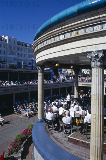 20059184 ENGLAND East Sussex Eastbourne View over the Promenade Band Stand with a brass band performing on a sunny day with spectators watching from deckchairs