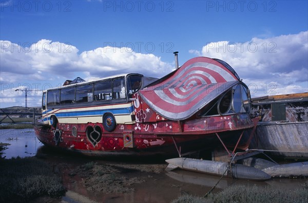 20059199 ENGLAND West Sussex Shoreham by Sea Colourful houseboat fabricated with various bus and car parts moored on the river Adur.