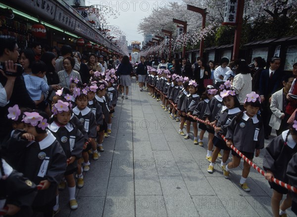 JAPAN, Asakusa, Tokyo, Nursery school children dressed for the flower festival on Buddhas birthday standing in line at the Senso Ji Temple Kannon temple.