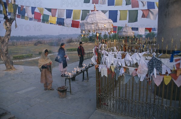 NEPAL, Lumbini, Pilgrims in front of the Ashoka pillar dating about 320 BC beside pond at sacred site where Buddha was born.