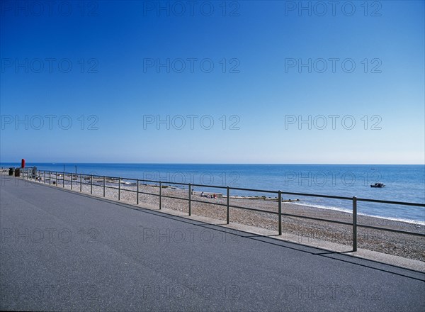 20059214 ENGLAND East Sussex Bexhill on Sea View from path across railings towards shingle beach and calm blue sea.