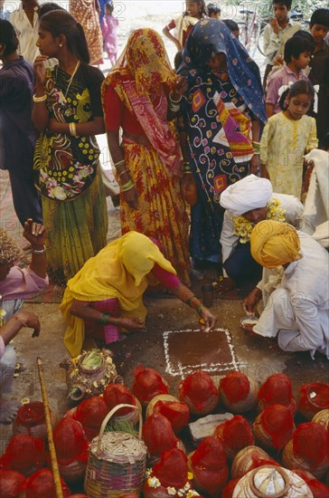 INDIA, Rajasthan, Udaipur, Mourners at memorial service for recently deceased man. Pots covered with red cloth contain holy Ganges water.