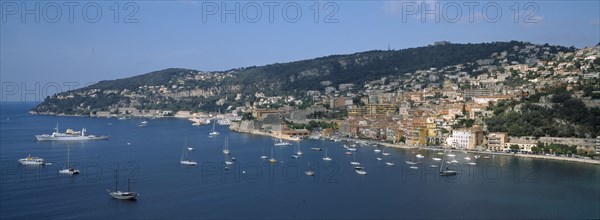 FRANCE, Provence Cote d Azur, Alpes Maritimes, Beaulieu sur Mer. View of the coastal town and moored boats seen from Cap Roux