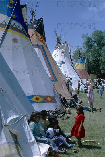 CANADA, Alberta, Calgary, Colourful Native North American Indian Tepees with people gathered on grass.