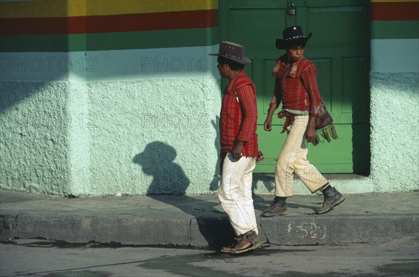 GUATEMALA, Huehuetanango, Mayan Indian men from the Sierra Los Cuchumatanes in street in Western Highland market town passing green painted door and wall.