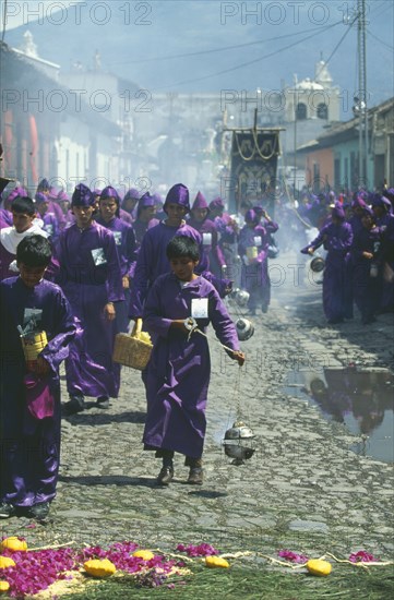 GUATEMALA, Antigua, Men and boys wearing traditional purple robes and burning incense in censers during Easter procession.