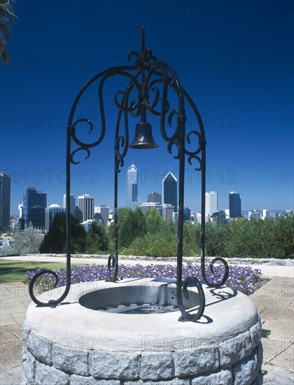 AUSTRALIA, Western Australia, Perth, Kings Park well with ornamental ironwork and bell with the city skyline beyond