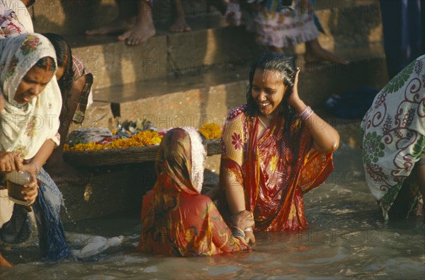 INDIA, Uttar Pradesh, Varanasi, Women wearing saris bathing in the sacred ghats on the River ganges.