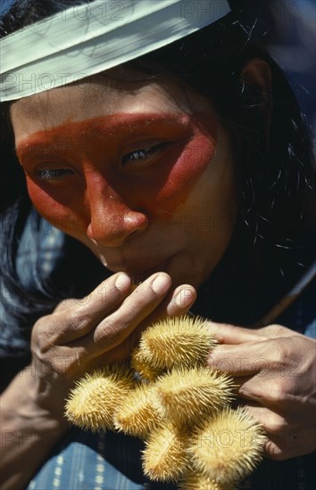 ECUADOR, Amazon, Auca Indian woman with achole plant from which the red colouring used as face paint is obtained.