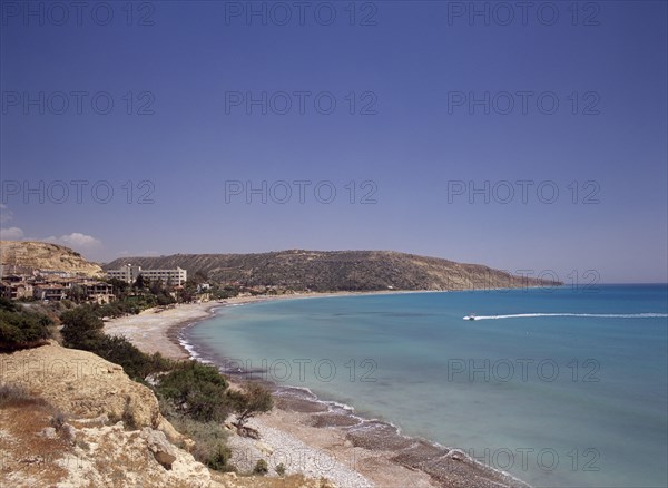 CYPRUS, Pissouri, Water skier and speed boat in Pissouri Bay encircled by quiet beach with surrounding rocky coastline overlooked by hotel and other buildings.