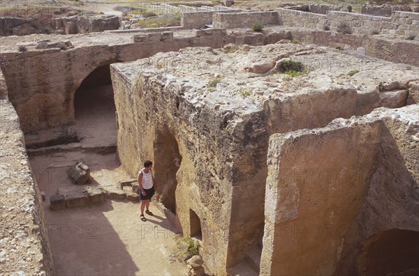 CYPRUS, Paphos, Tomb of the Kings with tourist looking through entrance.