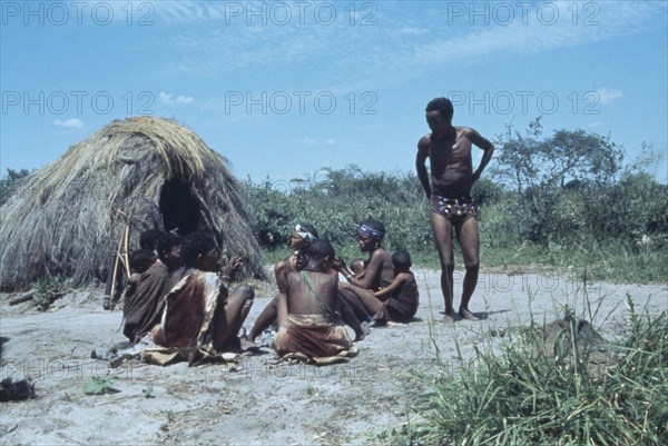 NAMIBIA, Kalahari Desert, Bushmen gathered next to straw hut.