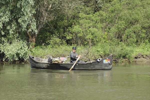 ROMANIA, Tulcea, Danube Delta, Fisherman transporting cycle and goods in a country boat in Danube Delta Biosphere Reserve