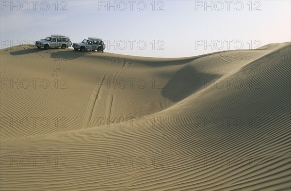 UAE, Baniyes Desert, Dune driving.  Two jeeps on ridge of wind rippled sand dune.