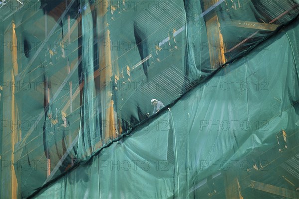 JAPAN, Shinjuku, Tokyo, Construction worker looking out from skyscraper safety netting.