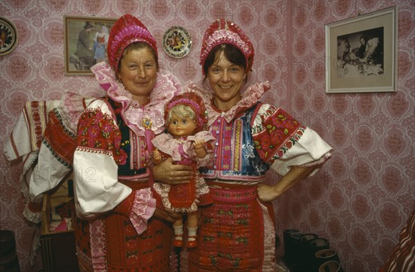 SLOVAKIA, Carpathian Mountains, Small Tatras, Helpa.  Two women holding doll all dressed in national costume.