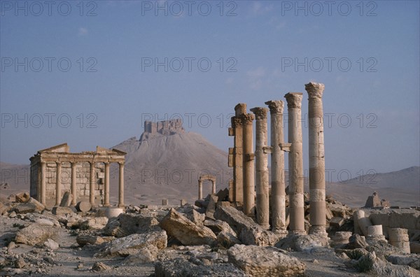 SYRIA, Palmyra, Roman ruins with columns and pillars and The Islamic Fort in the distance.