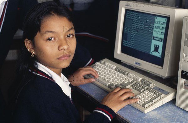 PERU, Lima, School girl learning computer sitting in class looking towards camera.