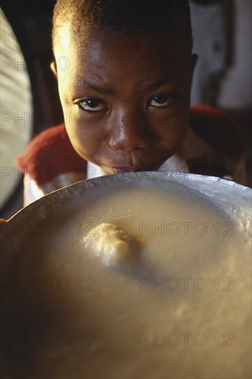 TANZANIA			, "				", Singida, Young boy next to bowl of breakfast at the Kititimo Centre School for street chldren.