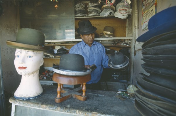 BOLIVIA, La Paz, El Alto.  Hat maker in La Ceja making traditional brown and grey bowler hats known locally as a bombin.