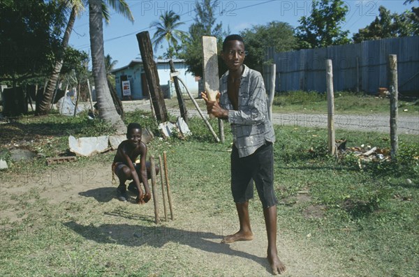 WEST INDIES, Jamaica, Clarendon, Boys playing cricket with home made bat and wickets.