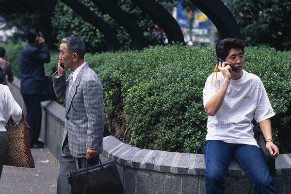 JAPAN, Shibuya, Tokyo, Three men ranging in age talking on mobile phones.