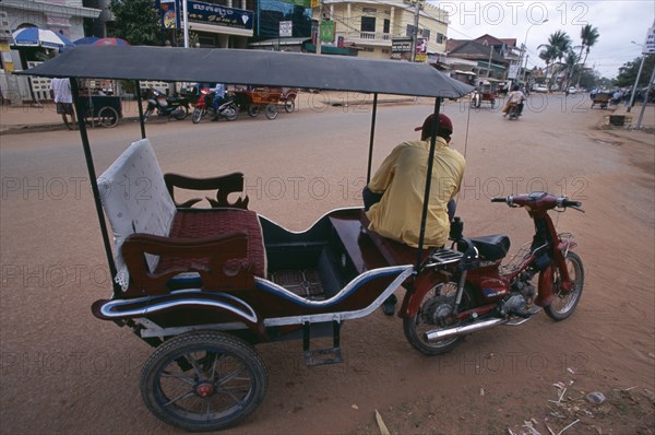 CAMBODIA, Siem Reap, Tuk tuk driver sitting on his motorbike in a quiet dusty street