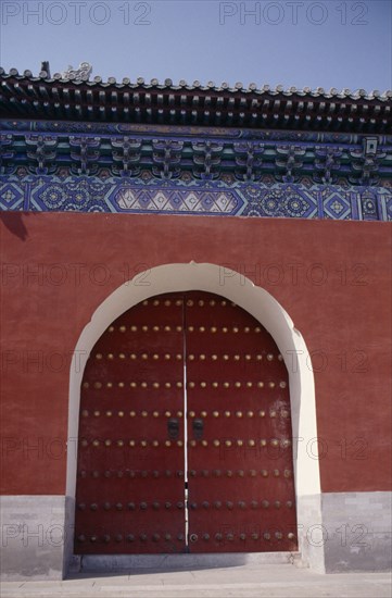 CHINA, Beijing, Temple of Heaven.  Detail of gateway set into red painted wall with decorative blue tiling above.