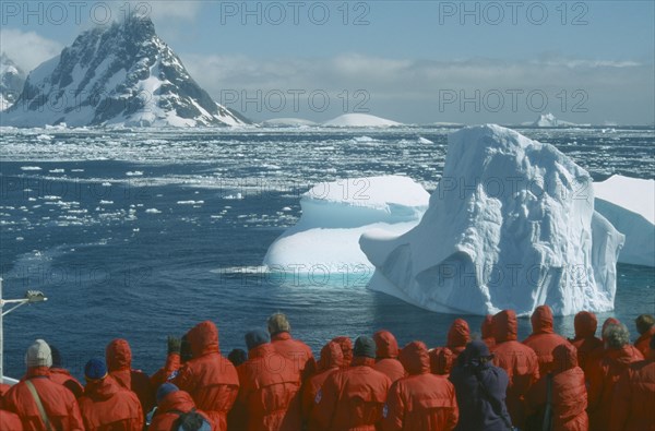 ANTARCTICA, Antarctic Peninsula, Tourists, Tourist group looking at iceberg from cruise ship near the Lemaire Channel.