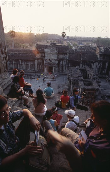 CAMBODIA, Siem Reap Province, Angkor Wat, Tourists with cameras watching the sunset from the central sanctuary on the upper level.