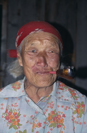 RUSSIA, Siberia, Lake Baikal, Portrait of elderly Buryat woman smoking pipe.