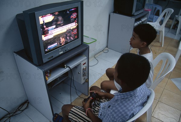 THAILAND, South, Bangkok, Two young boys playing a computer game in a shopping mall on Thanon Silom