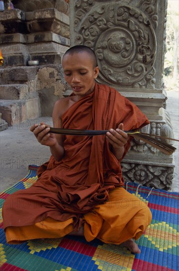 CAMBODIA, Siem Reap Province, Angkor Thom, Buddhist monk chanting from Sanskrit prayers inscribed on palm leaf.