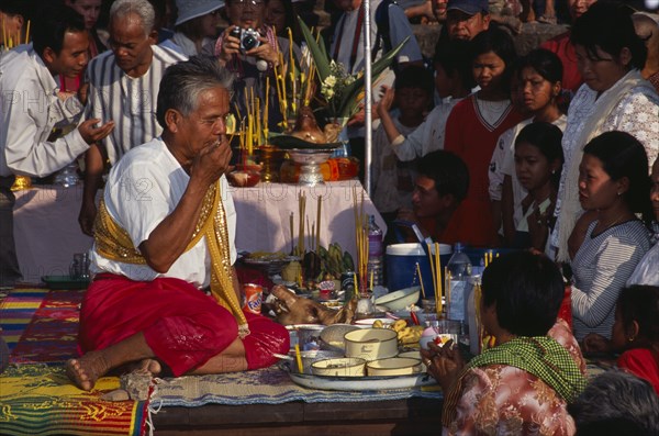 CAMBODIA, Siem Reap, Angkor Wat, Shaman at ceremony smelling the offerings of food brought by the Khmer people