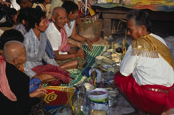 CAMBODIA, Siem Reap, Angkor Wat, Shaman at ceremony smelling the offerings of food brought by the Khmer people