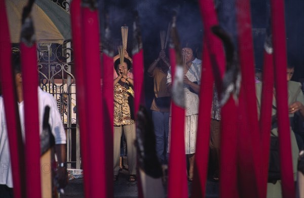 MALAYSIA, Penang, Georgetown, Kuan Yin Teng or Temple of Mercy with people carrying jos sticks and  praying in front of large jos sticks