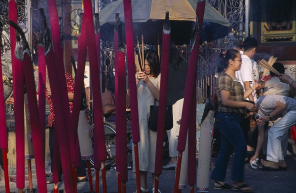 MALAYSIA, Penang, Georgetown, Kuan Yin Teng or Temple of Mercy with people carrying jos sticks and  praying in front of large jos sticks