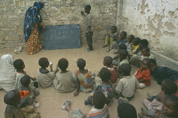 SOMALIA, Baidoa, Teacher with pupils in outdoor classroom at school in Baidoa orphanage.