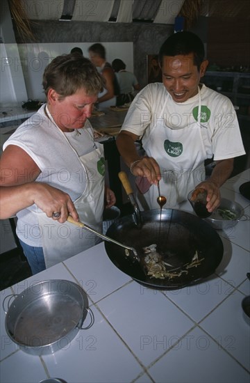 THAILAND, Krabi, Koh Lanta Yai, Cookery class at Time For Lime on Klong Dao beach. Instructor with tourist using a wok