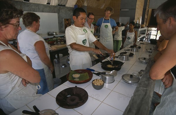 THAILAND, Krabi, Koh Lanta Yai, Cookery class at Time For Lime on Klong Dao beach. Instructor demonstrating the use of a wok to tourists