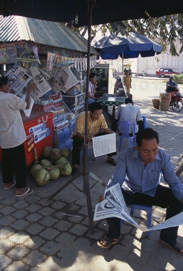 CAMBODIA, Siem Reap, Men reading newspapers at a drinks stall