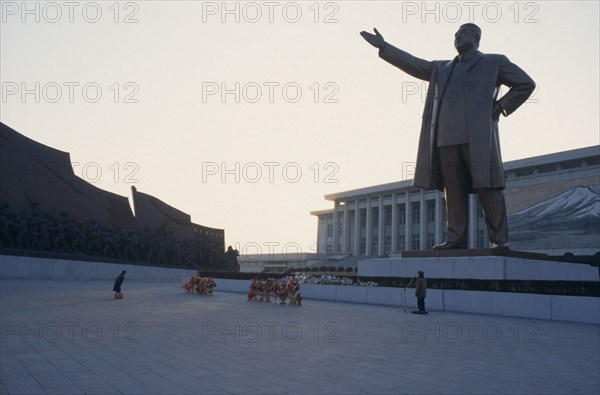 NORTH KOREA, Pyongyang, "Woman bowing in respect in front of statue of Kim II Sung, the Grand Monument."