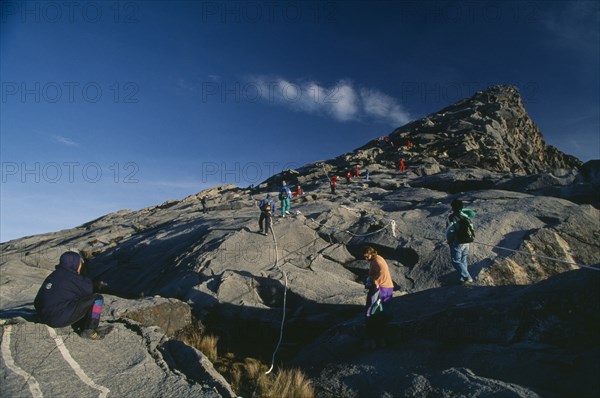 MALAYSIA, Borneo, Sabah, Tourists approaching Lows Peak the summit of Mount Kinabalu.